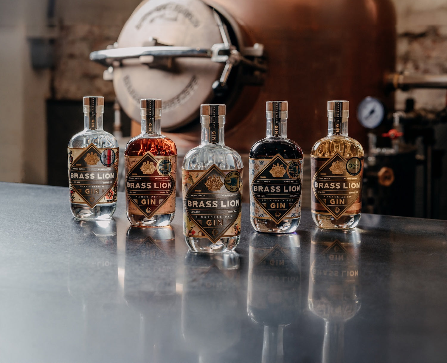Close-up of Brass Lion gin bottles in front of a distillery still, adapted for mobile view.